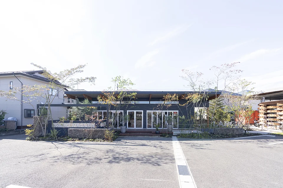 昼間の施設外観と植栽に囲まれたウリンデッキ施工事例