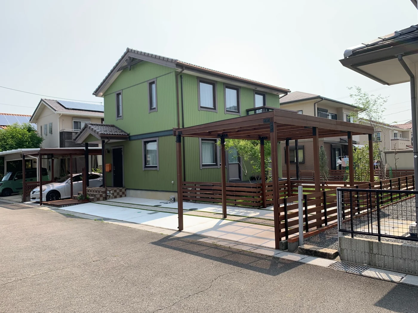 住宅・駐車場・パーゴラ・庭が一体で見える外構全景。
