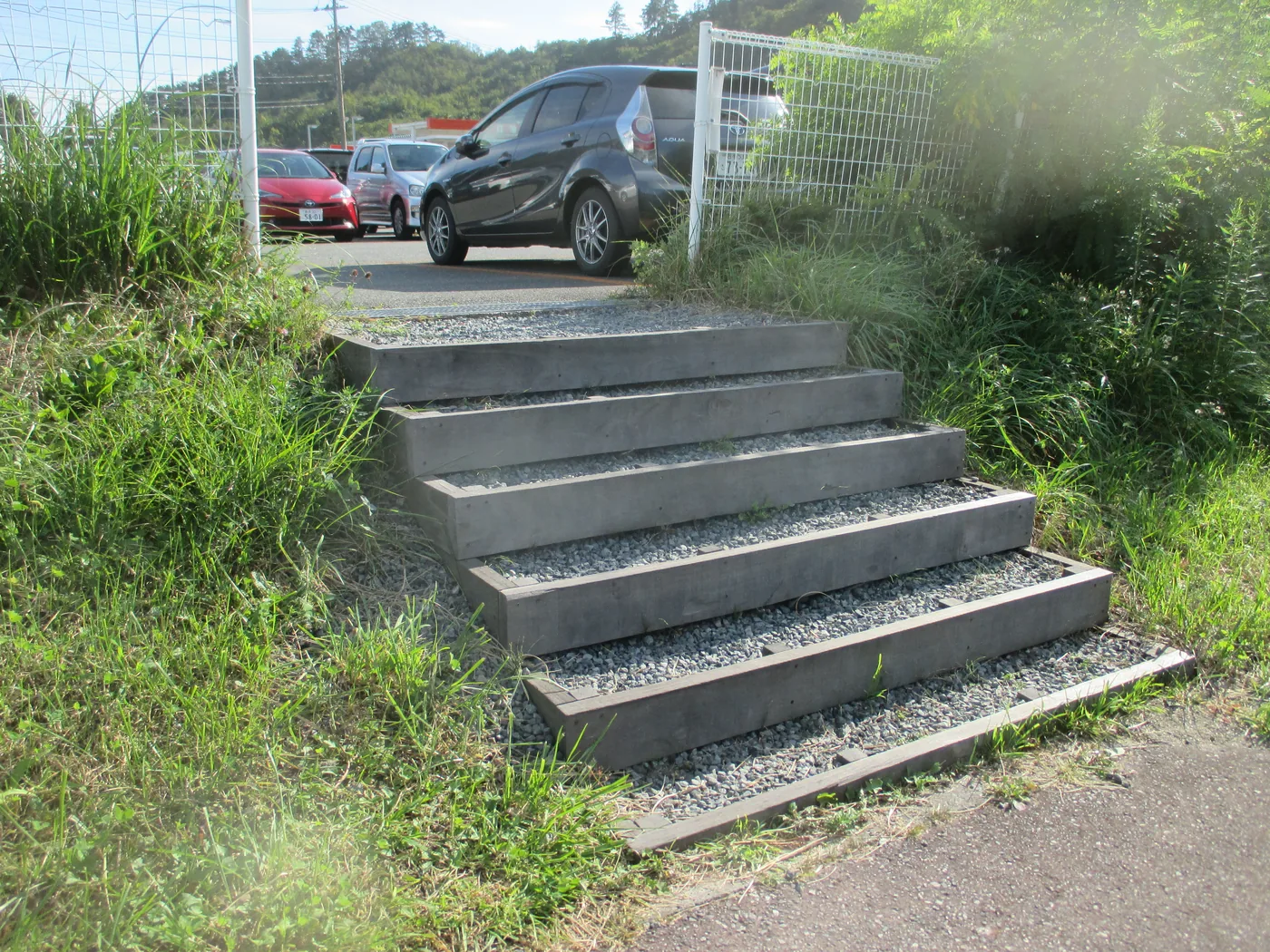 道路と高低差のある敷地をつなぐウリン枠と砂利踏面の屋外階段を上下の空間とともに見る全景