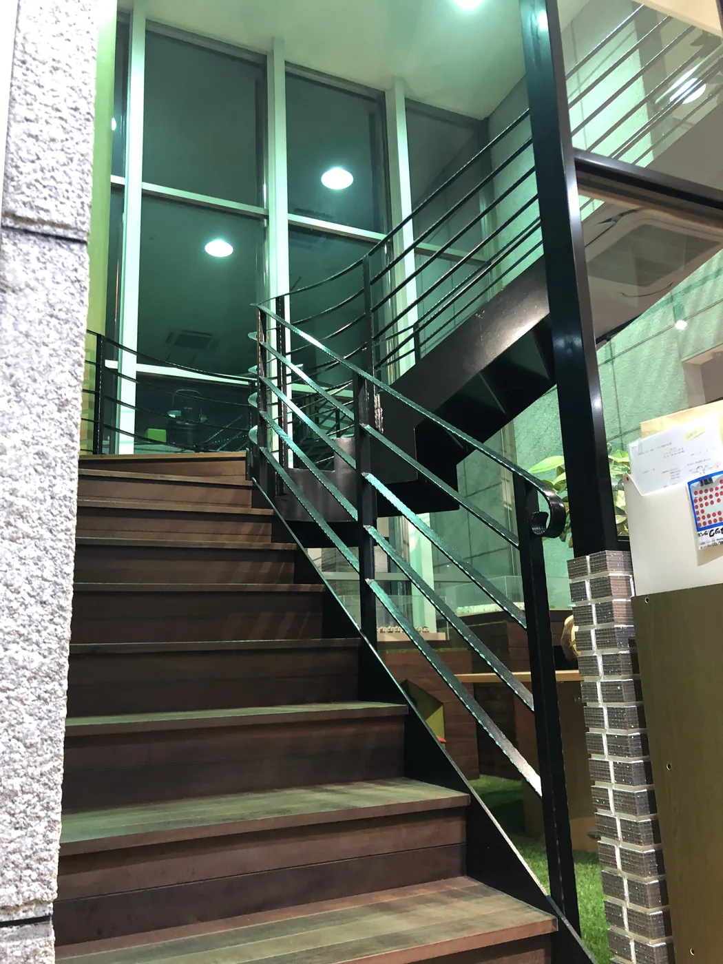 ウリンの段板と曲線的な鉄製手すりを組み合わせた階段を上下の空間とともに見る全景