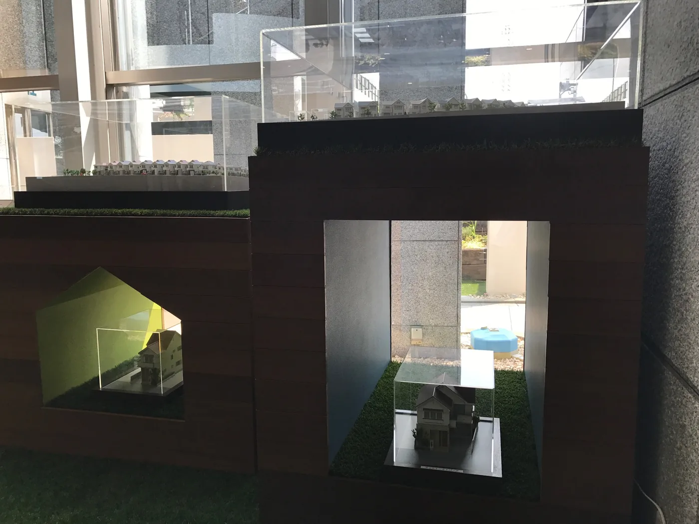 高さの異なる台、壁際の立ち上がり、入口まわりを同じ木でそろえ、展示の背景を統一しています
