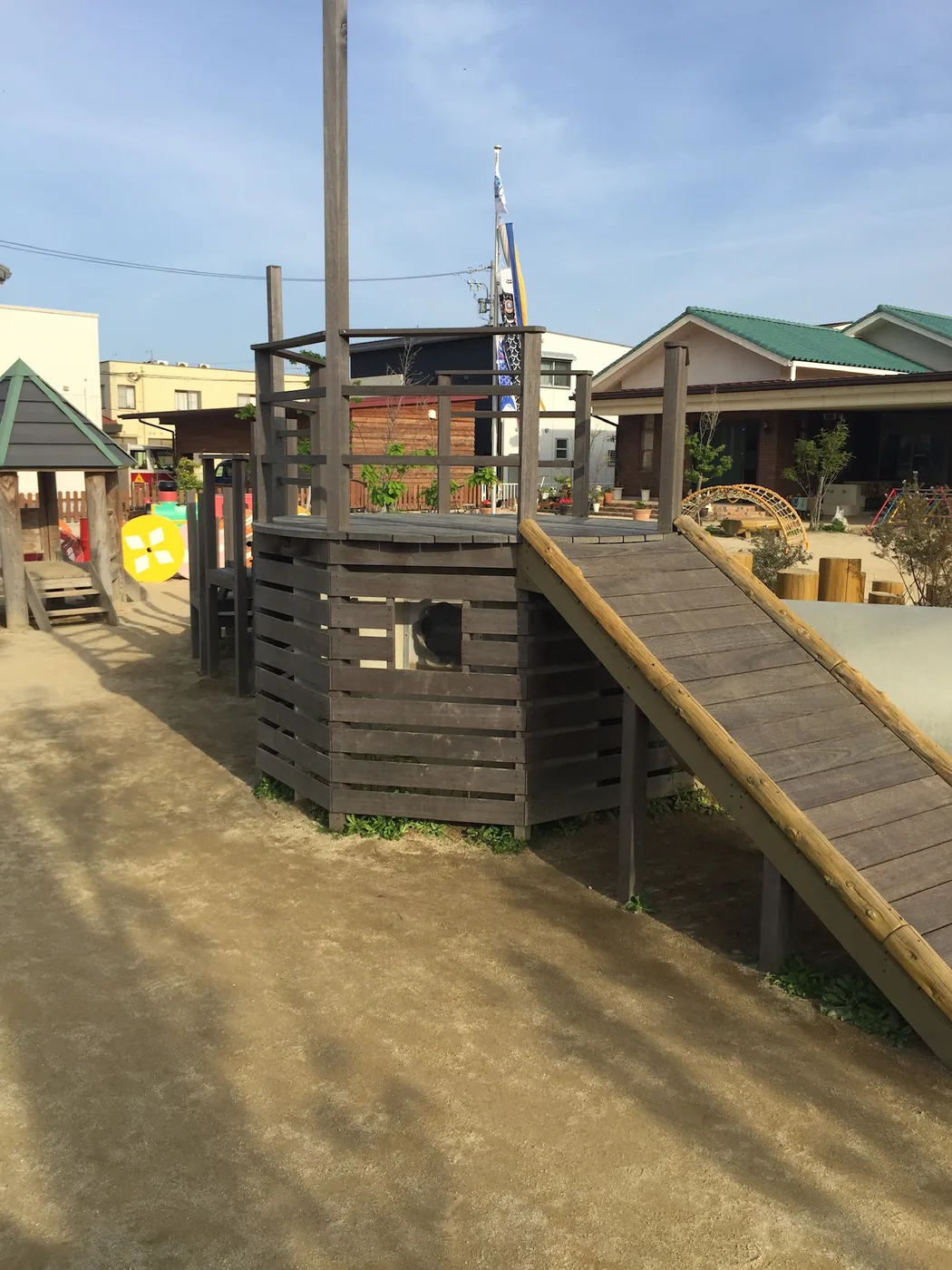 階段、スロープ、トンネルを組み合わせた屋外のウリン遊具デッキを施設の環境とともに見る全景