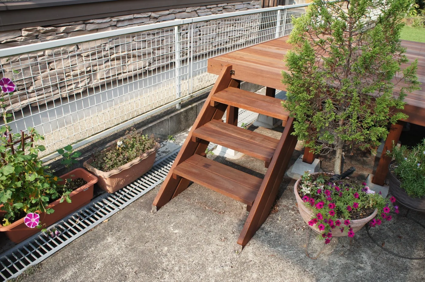 建物沿いの長い床と庭へ張り出す短い床をL字につなぎ、角と端部に階段を設けています