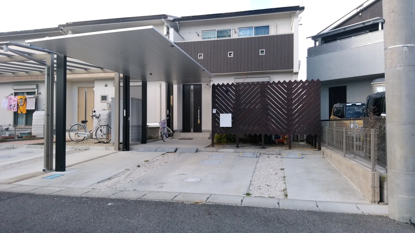 カーポート奥の玄関前へ設けた斜め格子ウリンスクリーンと周囲の庭・建物を一緒に見る全景