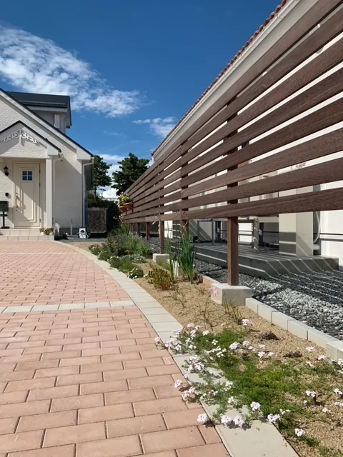 曲線アプローチと横板フェンスを見渡す住まいの外観