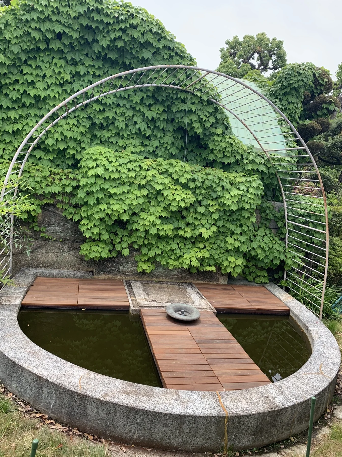 金属フレーム越しに見た円形池とウリン通路