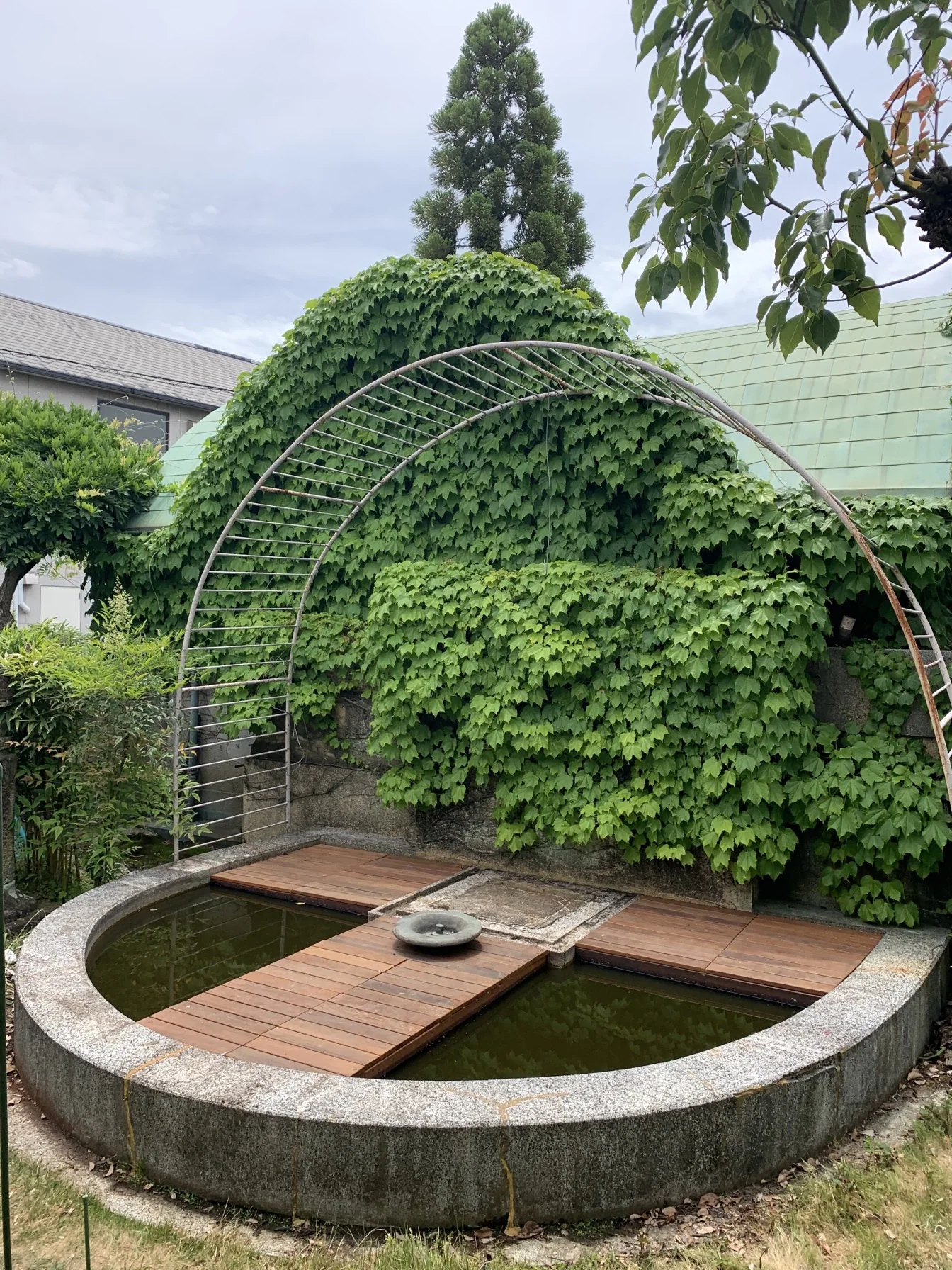 庭の植栽に囲まれた池上デッキの縦景