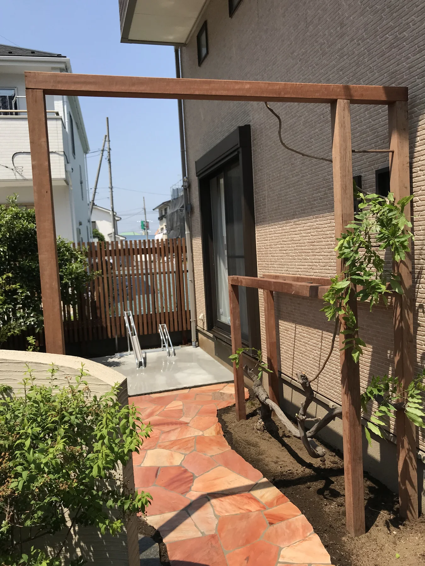 曲線アプローチとウリン縦格子フェンスを見渡す前庭全景