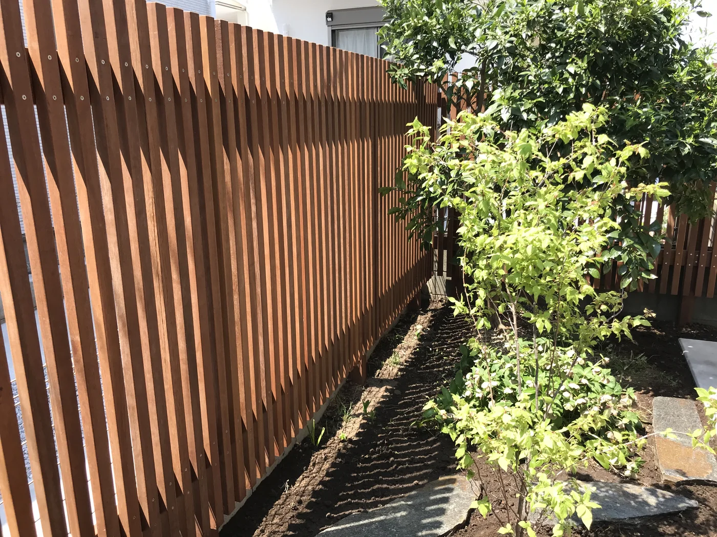 植栽に沿って連続するウリン縦格子フェンスの近景