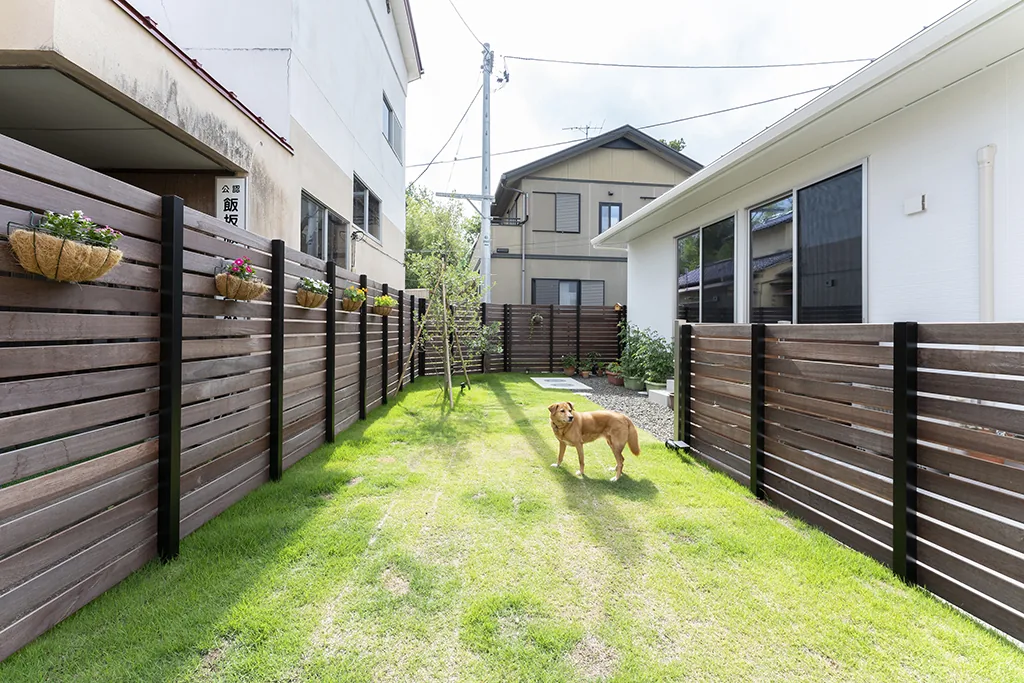 黒い柱と横板が長く続く庭の全景