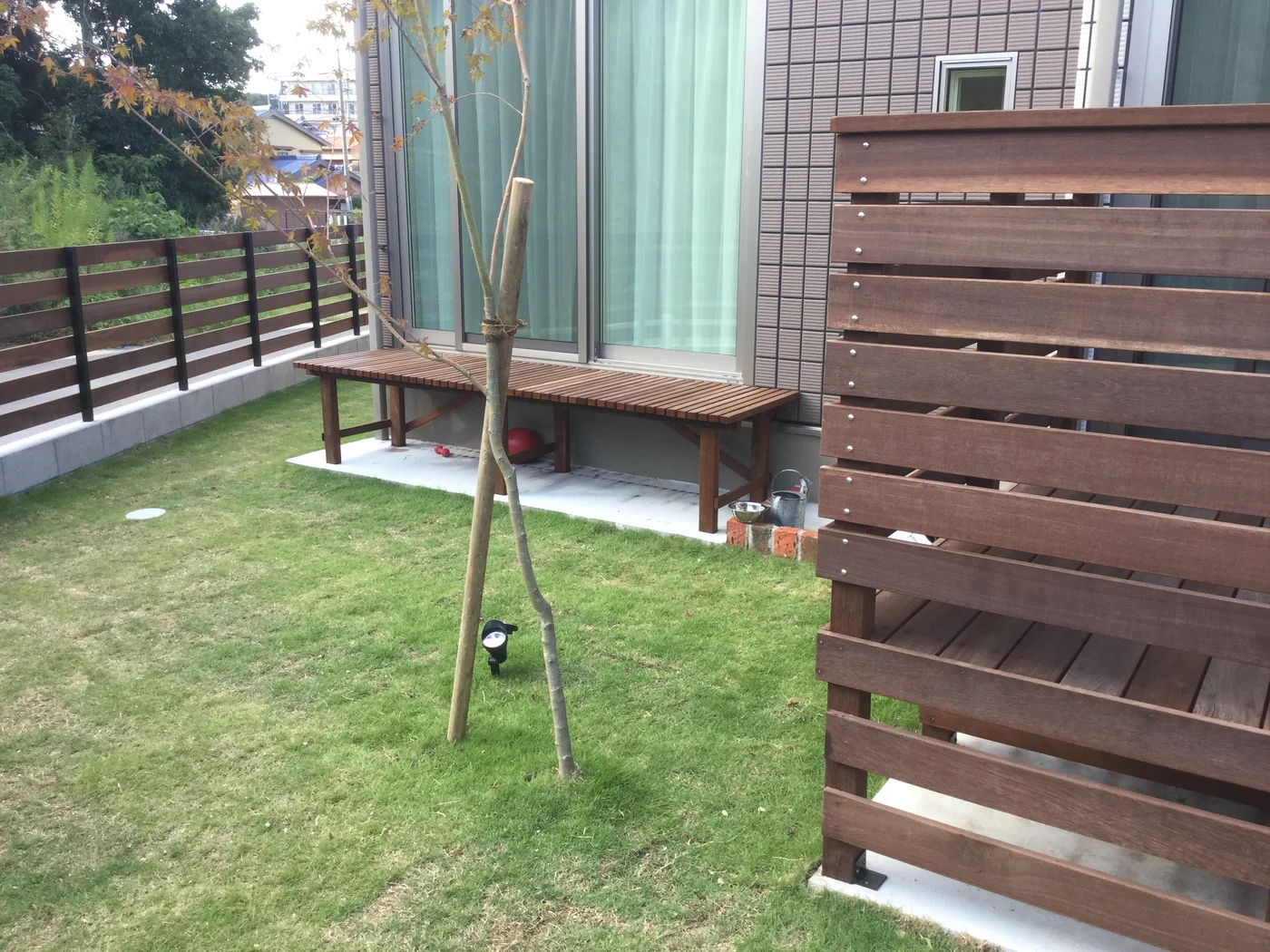 樹木とデッキを囲むウリン横板フェンス