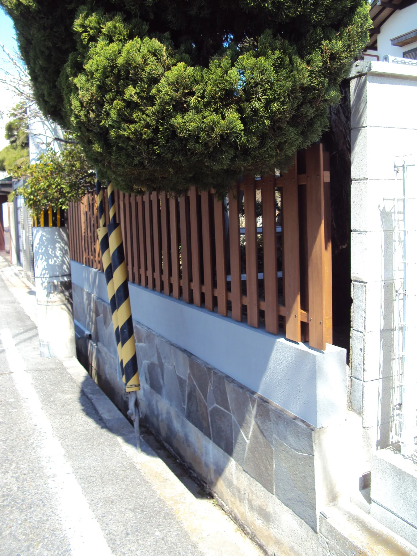 曲線道路に沿って続く縦格子フェンス