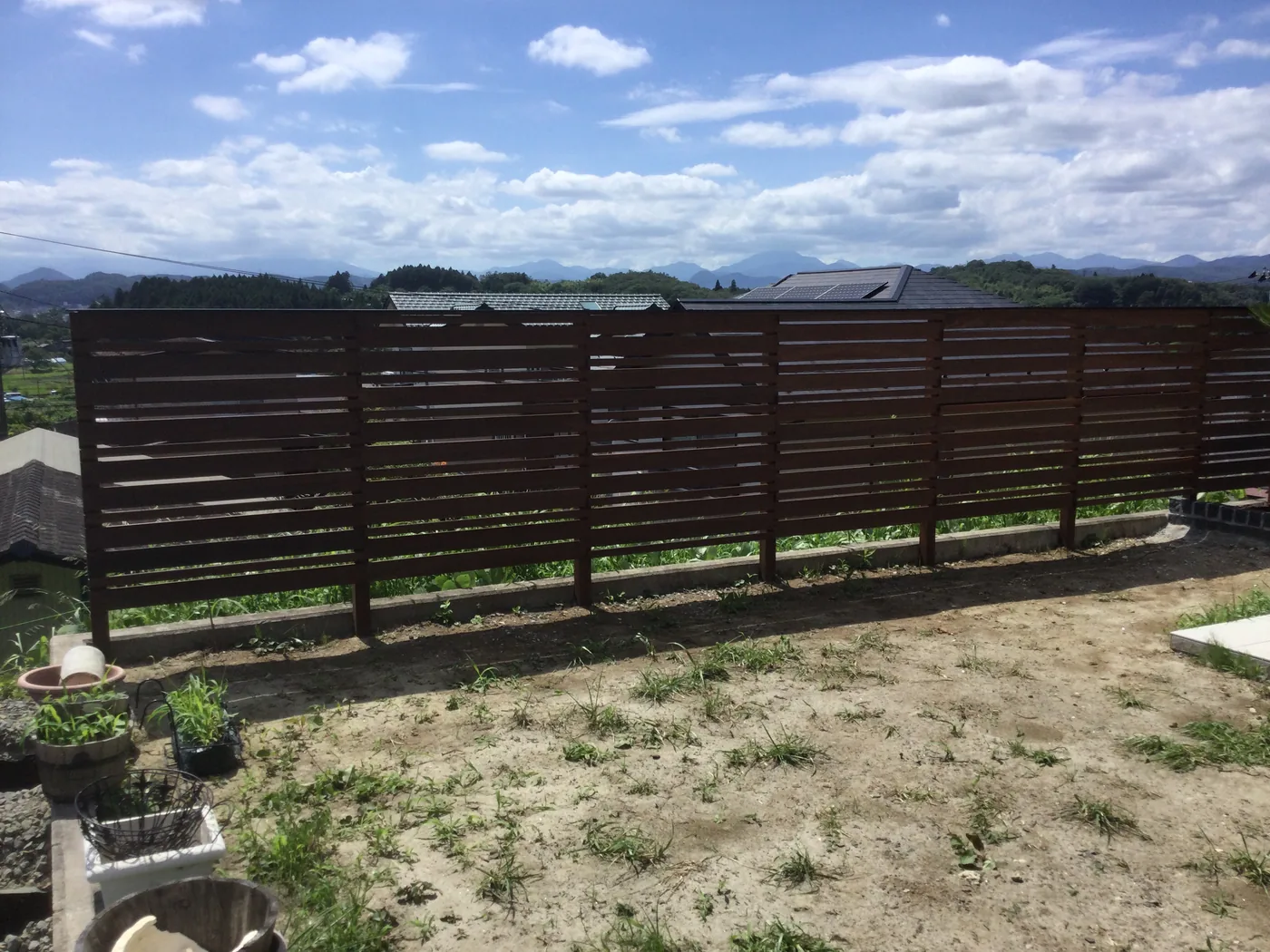 山並みを背景にウリンフェンスとベンチを見渡す庭全景