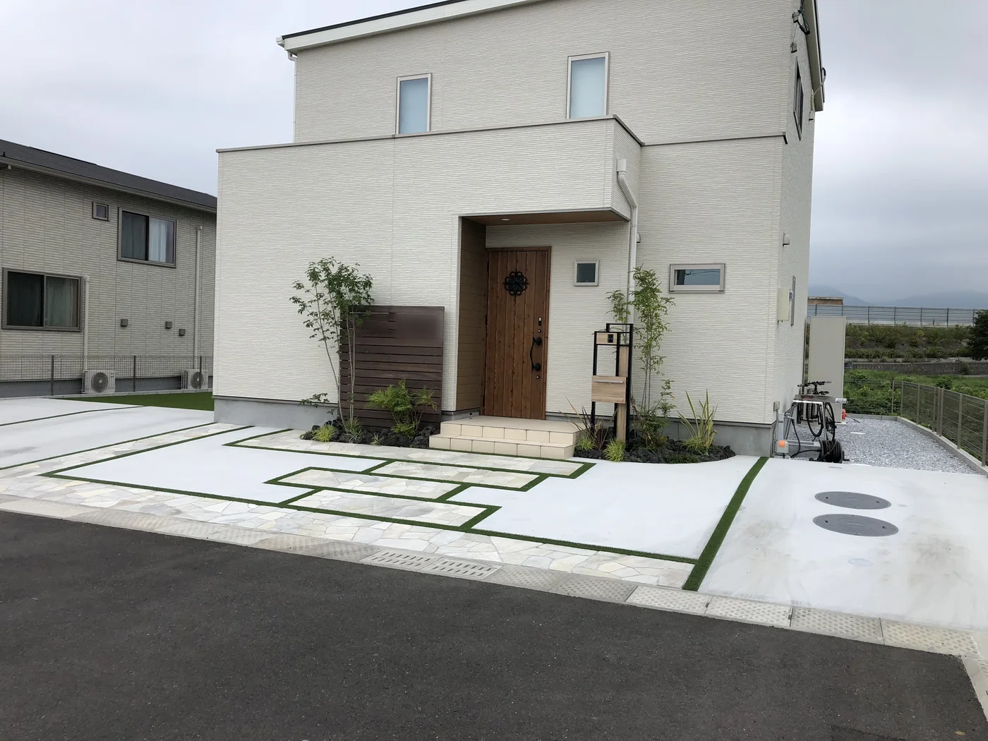 道路側から見る白い住宅と玄関外構全景