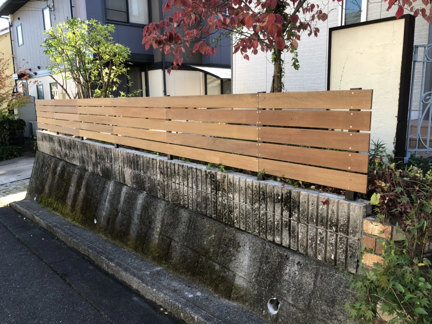 住宅と植栽を背景にした横板フェンス