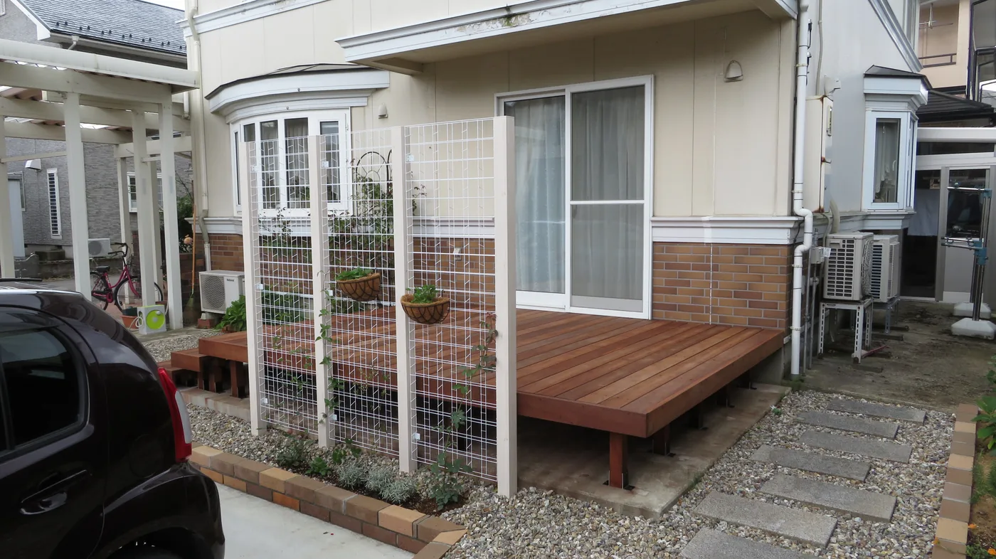 白いトレリスと植栽に囲まれた窓前デッキ全景