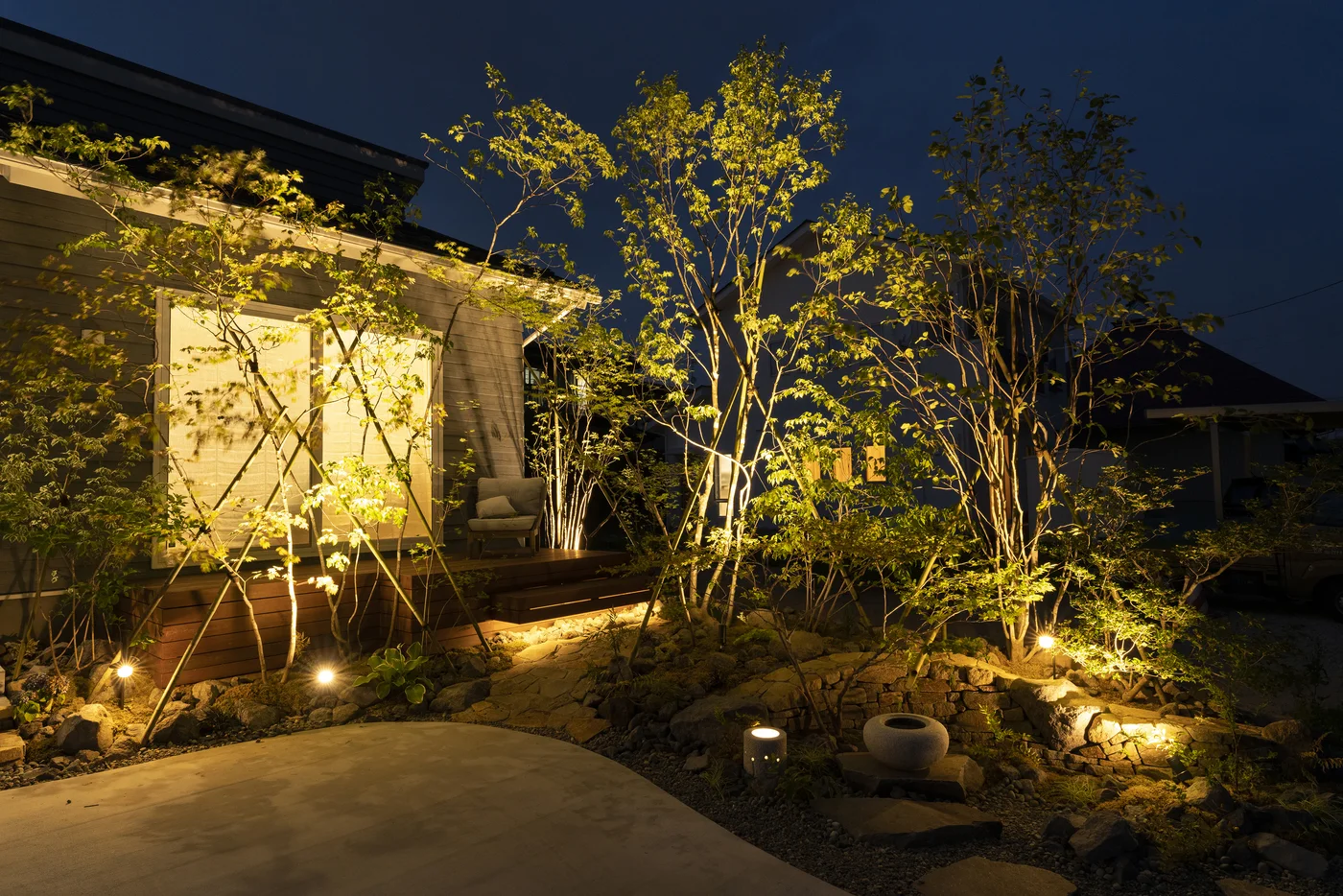 樹木の間から光が広がる庭アプローチの夜景