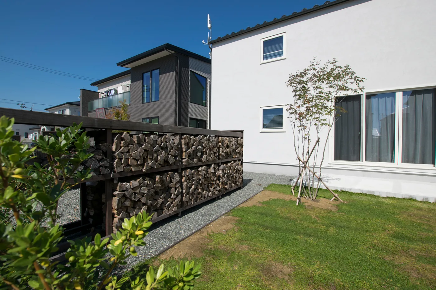 芝生側から見る長いウリン薪棚と庭の全景