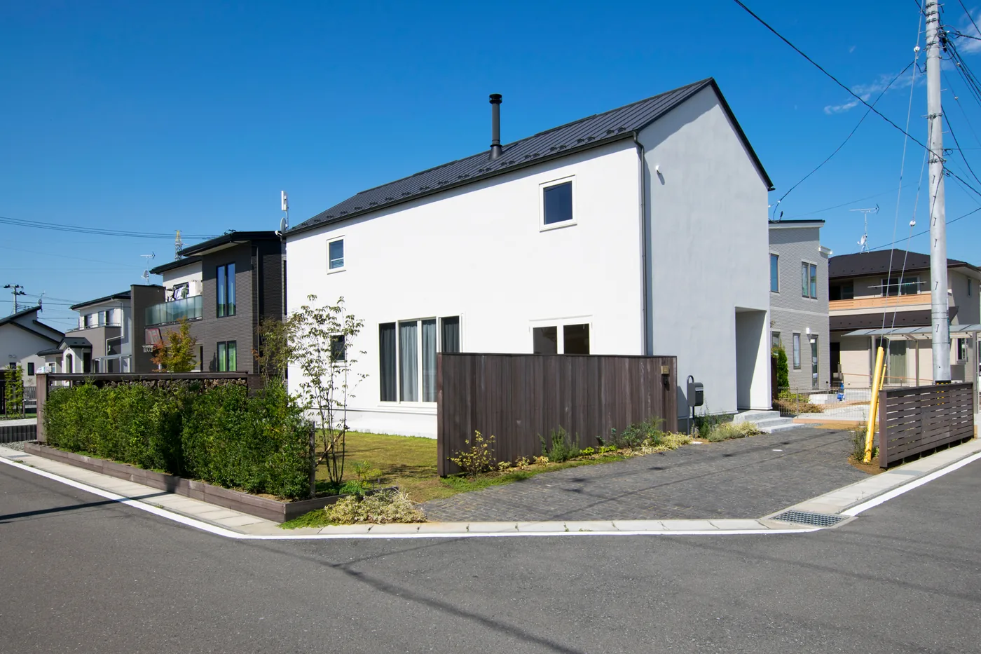 角地の白い住宅と低いウリン横板フェンスの全景
