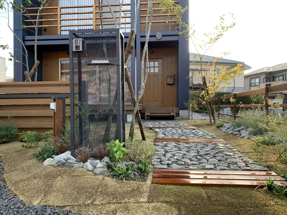 石敷きアプローチとウリン材のステップ・フェンスが見える住宅外構の施工事例