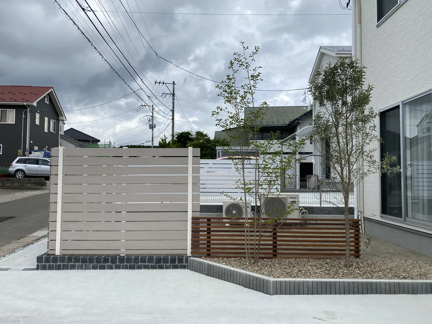 玄関前の植栽帯と二段階のフェンスを道路側から見る