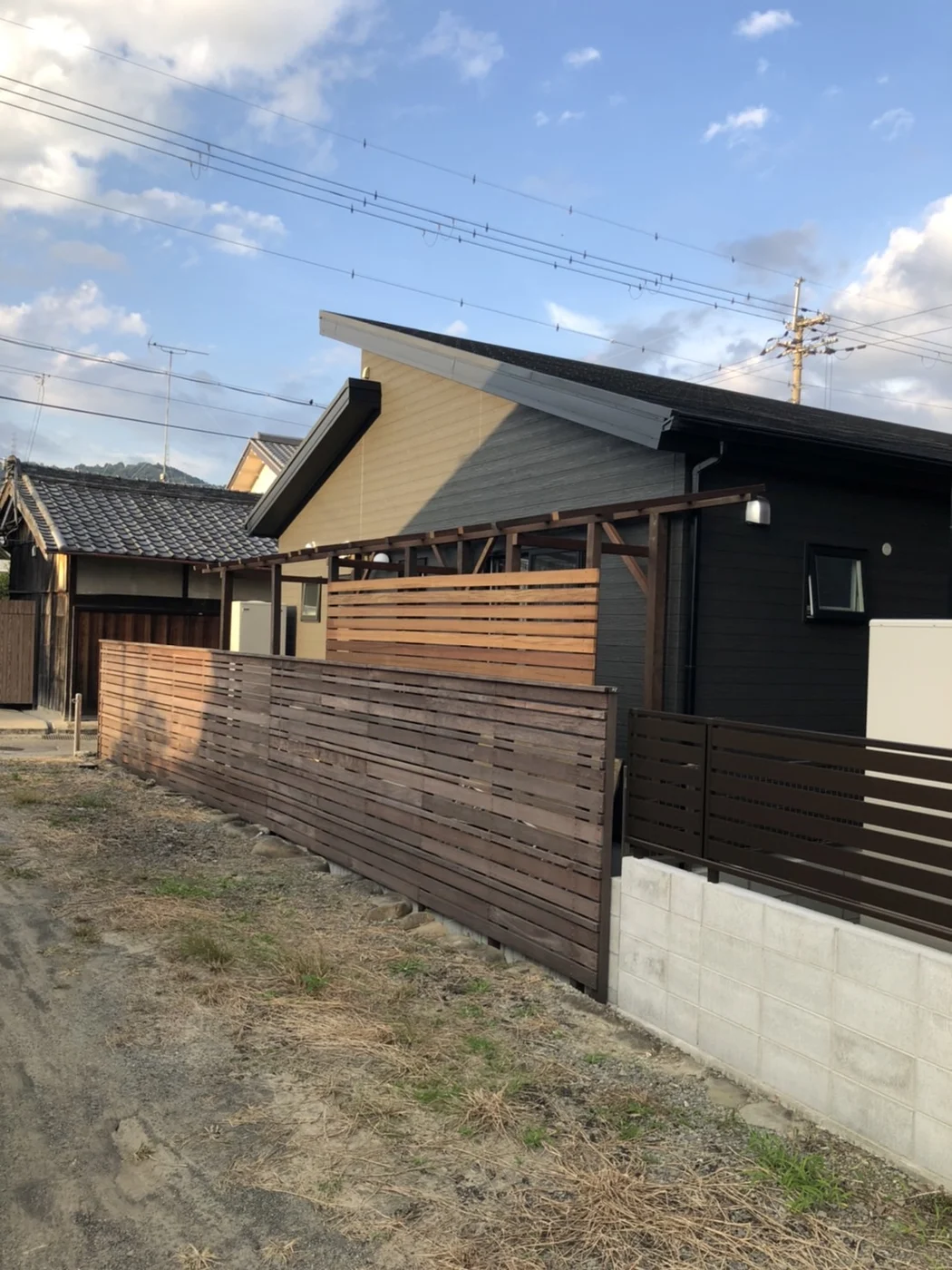 住宅沿いに長く続く横板フェンスと屋根フレームを見た全景です