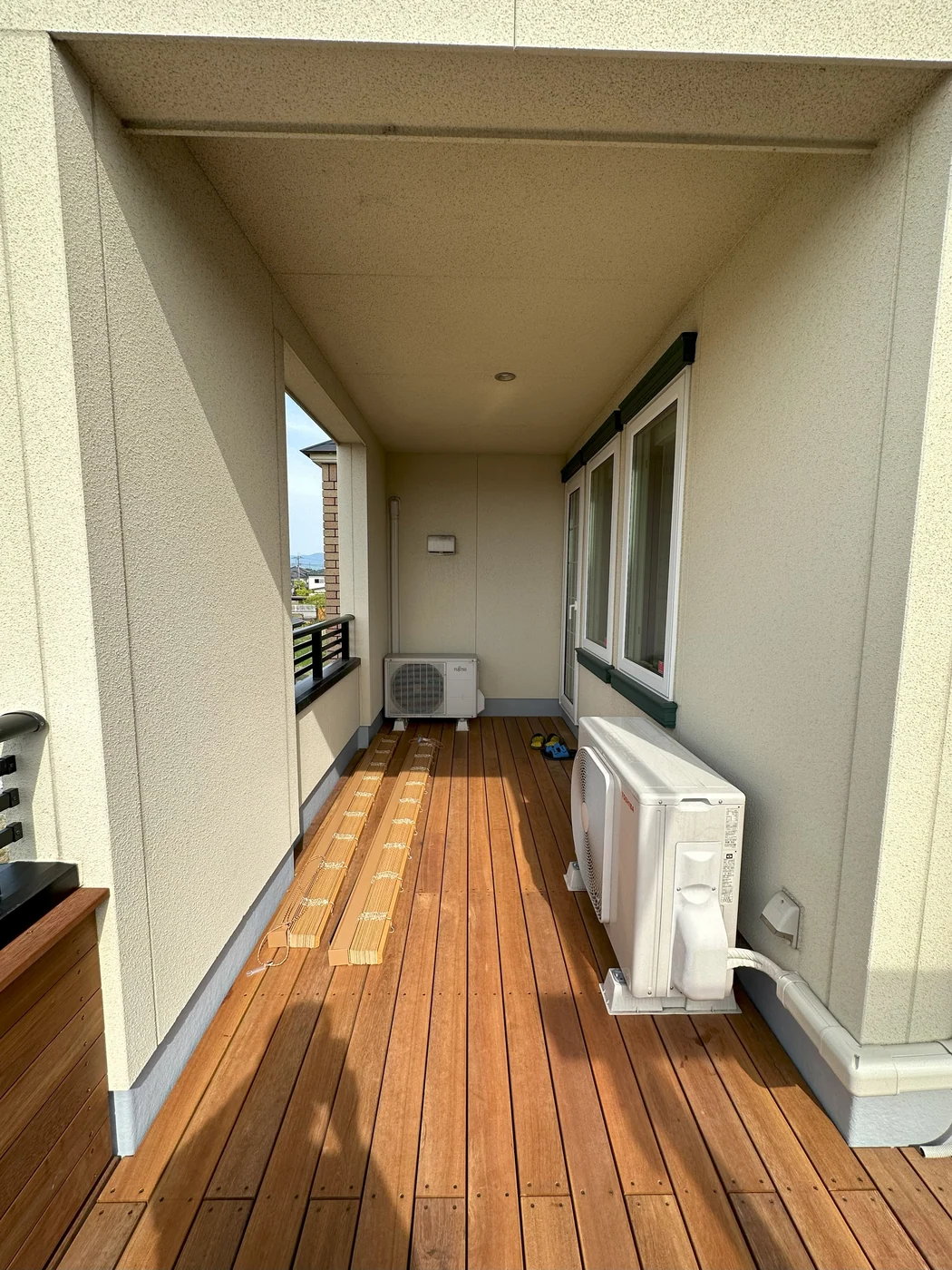 室外機の脇を通る木の床と建物の軒下